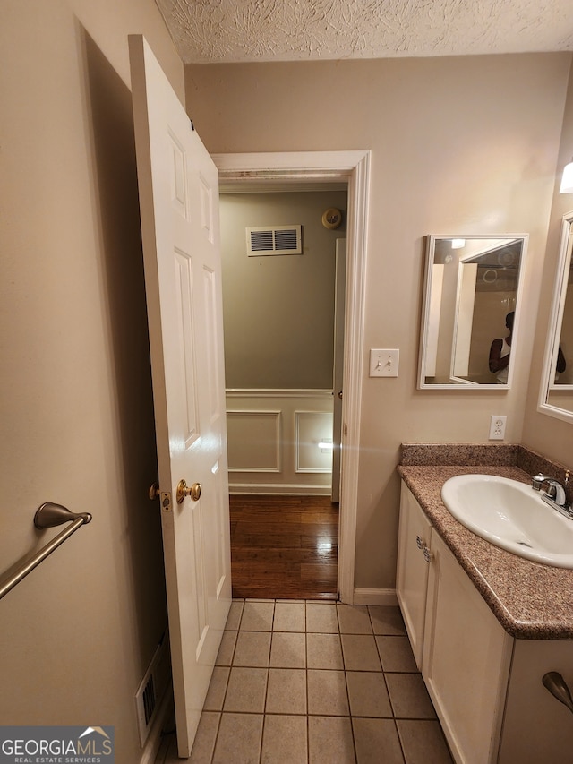 bathroom with vanity, wood-type flooring, and a textured ceiling