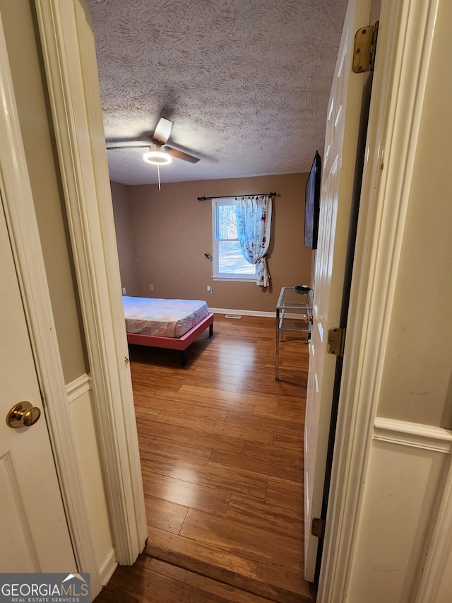 unfurnished bedroom with hardwood / wood-style floors, ceiling fan, and a textured ceiling