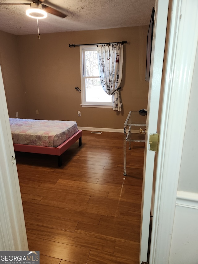 bedroom with hardwood / wood-style floors, a textured ceiling, and ceiling fan