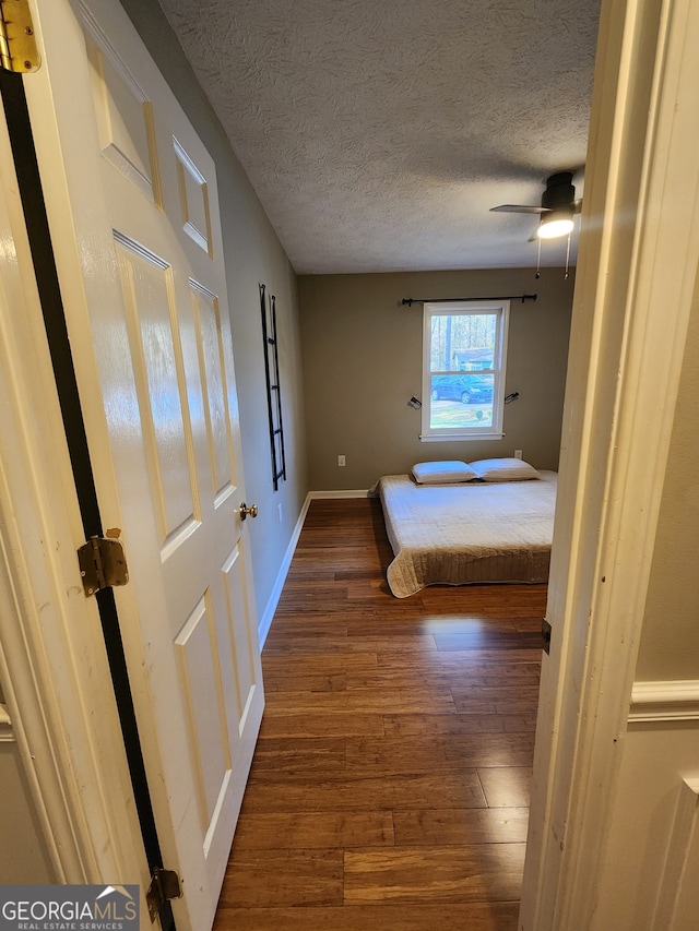 unfurnished bedroom featuring dark hardwood / wood-style floors, ceiling fan, and a textured ceiling