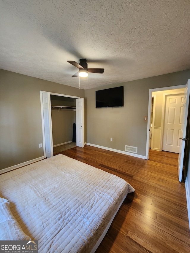 bedroom featuring wood-type flooring, a textured ceiling, a closet, and ceiling fan