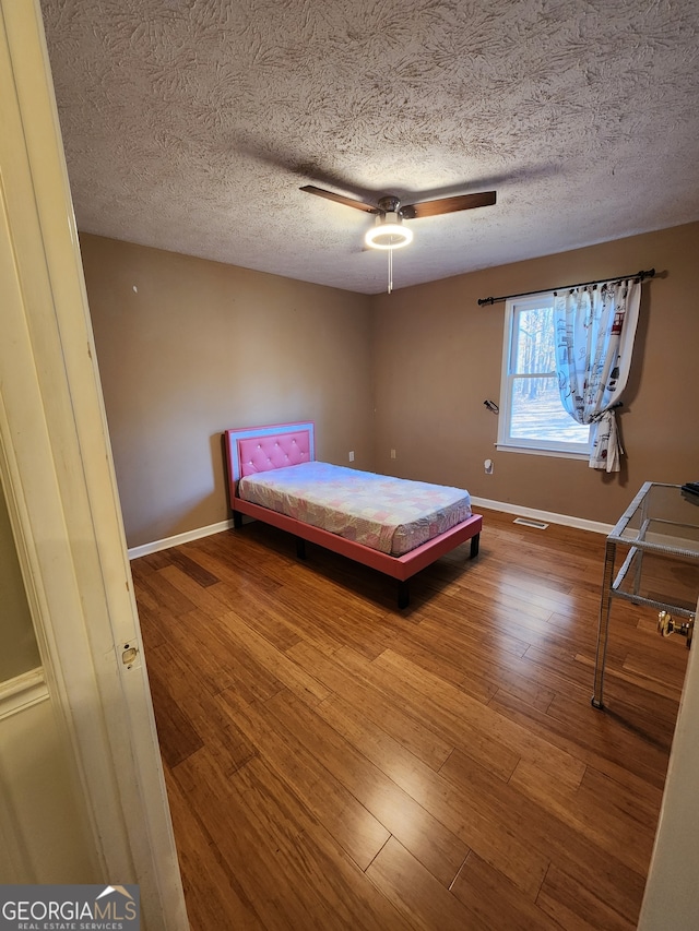 unfurnished bedroom featuring ceiling fan, hardwood / wood-style floors, and a textured ceiling