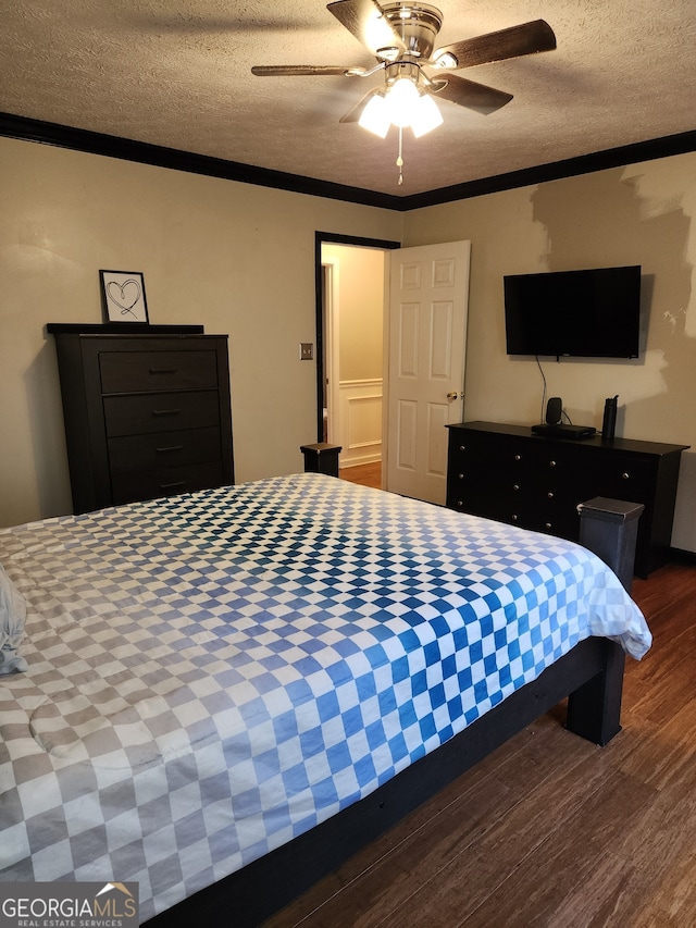 bedroom featuring a textured ceiling, ceiling fan, ornamental molding, and dark wood-type flooring