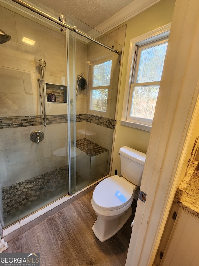 bathroom featuring walk in shower, crown molding, wood-type flooring, a textured ceiling, and toilet