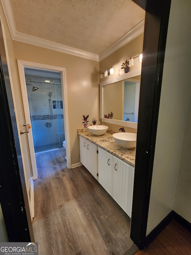 bathroom featuring hardwood / wood-style floors, a textured ceiling, an enclosed shower, and ornamental molding