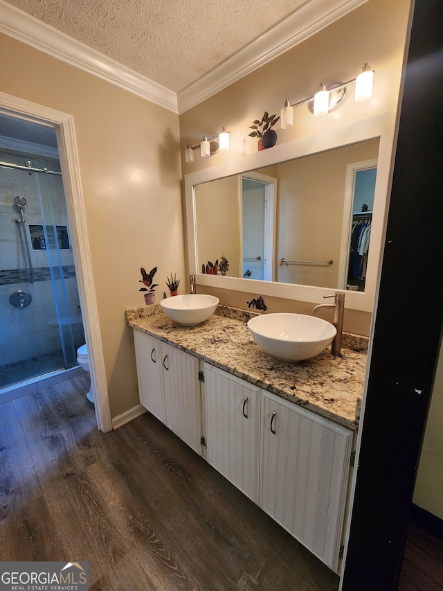 bathroom with an enclosed shower, a textured ceiling, crown molding, wood-type flooring, and toilet