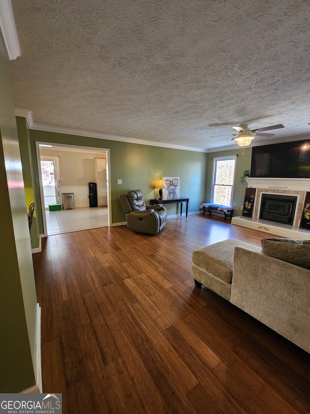 living room with hardwood / wood-style flooring, ceiling fan, ornamental molding, and a textured ceiling