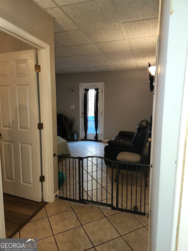 hallway featuring tile patterned flooring and a paneled ceiling