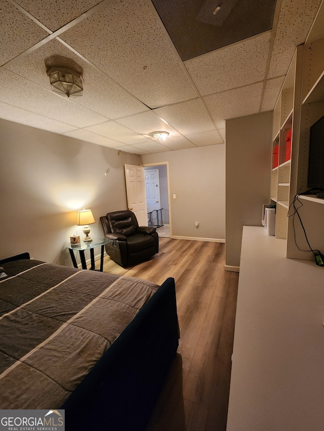 bedroom with a paneled ceiling and wood-type flooring