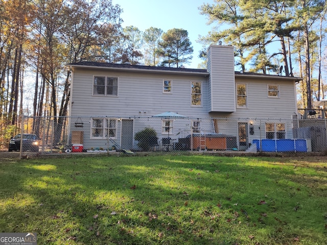 rear view of property with a yard and a hot tub