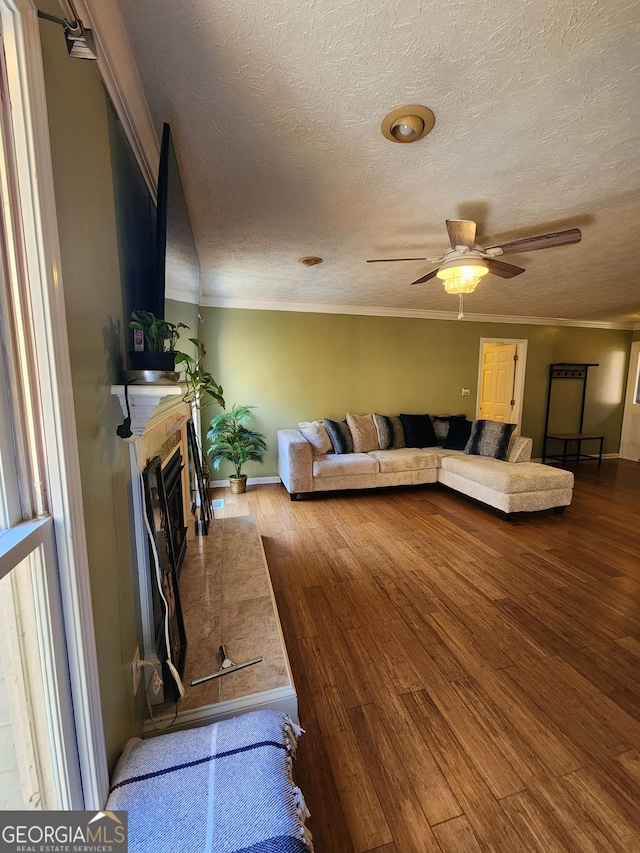 living room with a tile fireplace, wood-type flooring, a textured ceiling, and ceiling fan