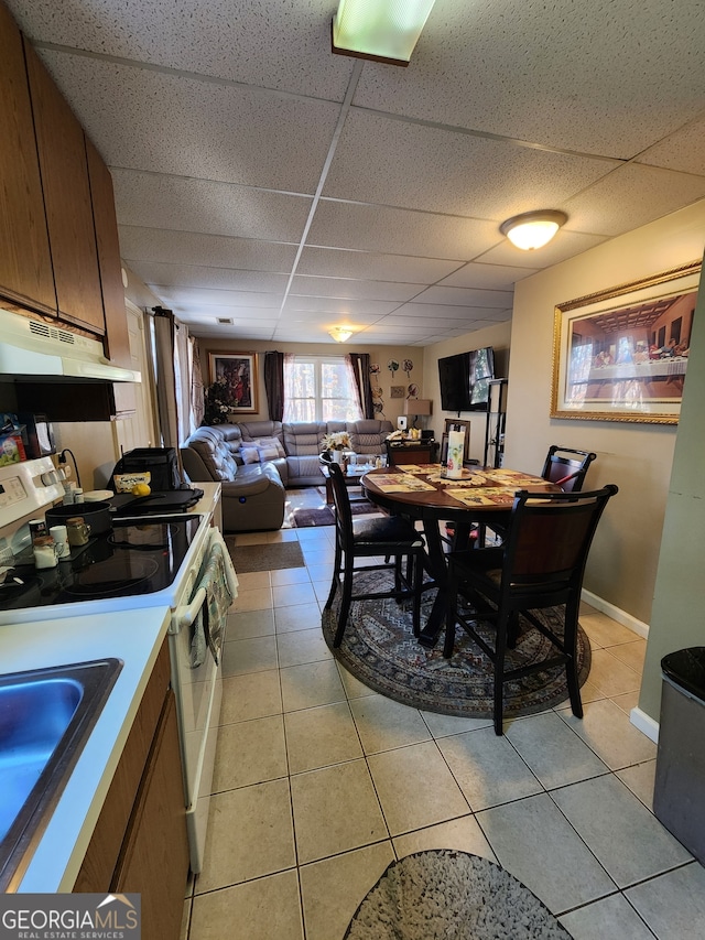 dining room featuring a paneled ceiling, light tile patterned flooring, and sink