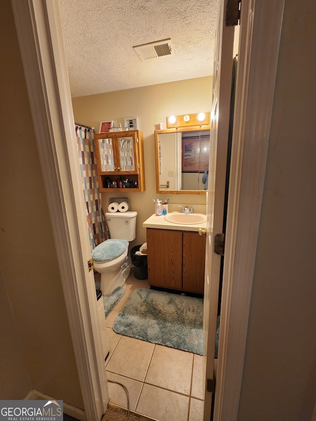 bathroom featuring tile patterned floors, vanity, toilet, and a textured ceiling