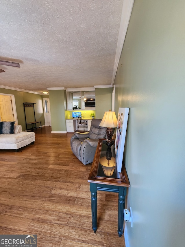 living room with wood-type flooring, a textured ceiling, and ornamental molding