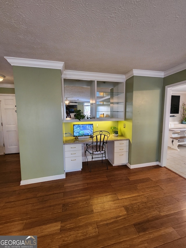 office featuring a textured ceiling, dark hardwood / wood-style flooring, built in desk, and ornamental molding