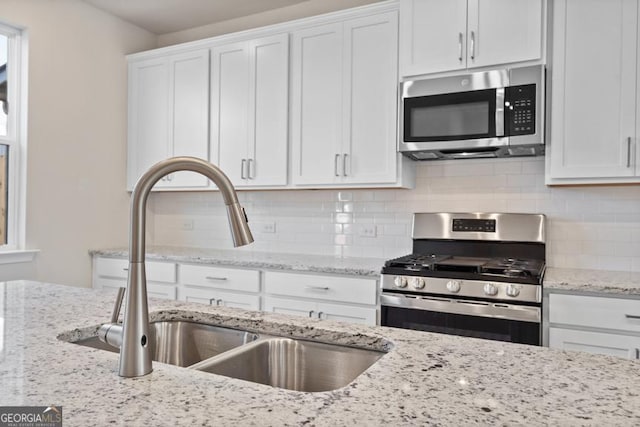 kitchen featuring decorative backsplash, white cabinetry, sink, and appliances with stainless steel finishes