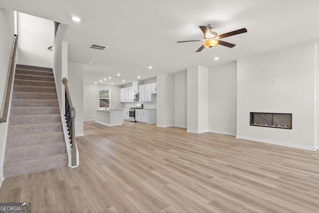 unfurnished living room with ceiling fan and light hardwood / wood-style flooring