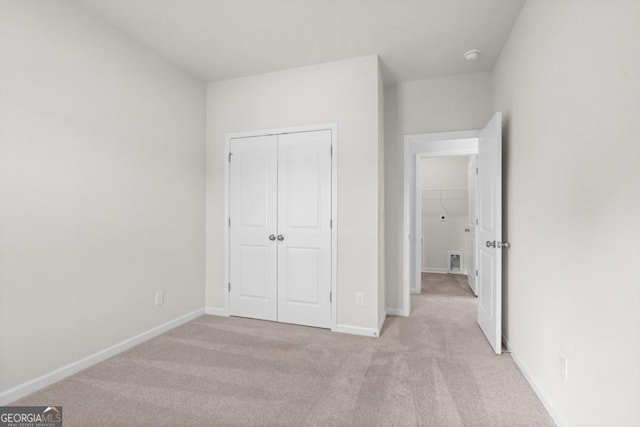 unfurnished bedroom with light colored carpet and a closet