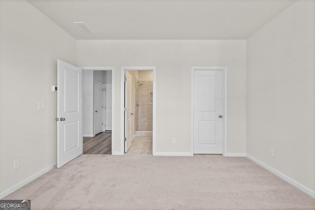 unfurnished bedroom with light colored carpet and connected bathroom