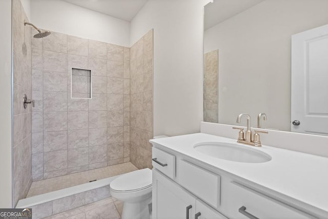 bathroom featuring a tile shower, vanity, toilet, and tile patterned floors