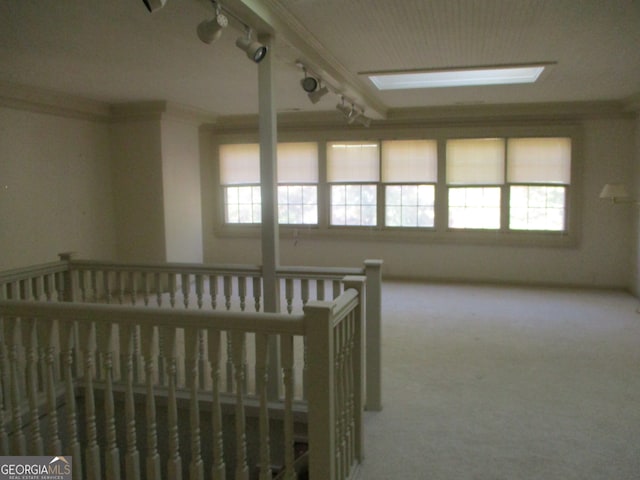 unfurnished bedroom featuring carpet floors, a crib, crown molding, and rail lighting