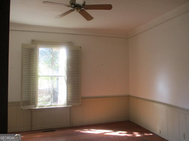 unfurnished room featuring hardwood / wood-style floors, ceiling fan, a healthy amount of sunlight, and wooden walls