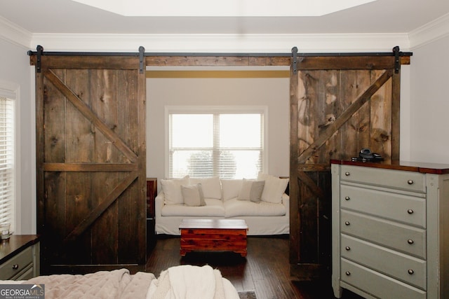 sitting room with a barn door, crown molding, and dark wood-type flooring