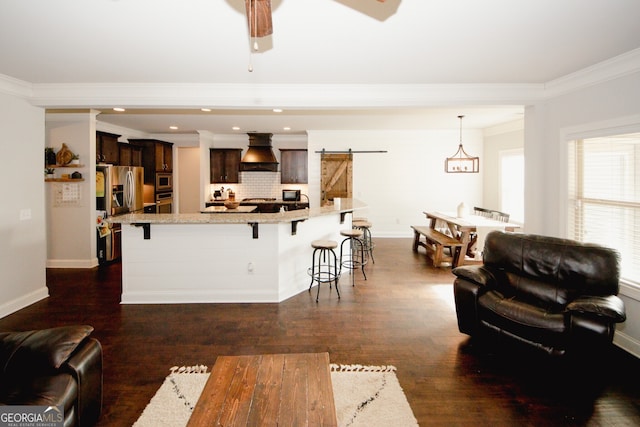 kitchen featuring sink, a barn door, dark brown cabinetry, a kitchen island, and custom range hood