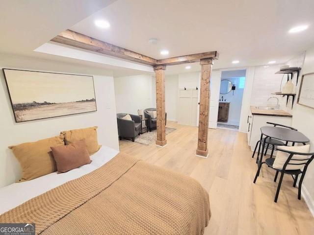 bedroom featuring light hardwood / wood-style floors, a barn door, and sink