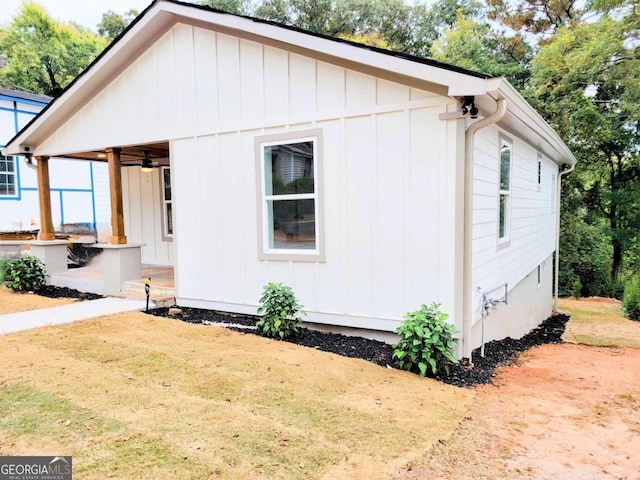 view of side of property featuring ceiling fan and a lawn