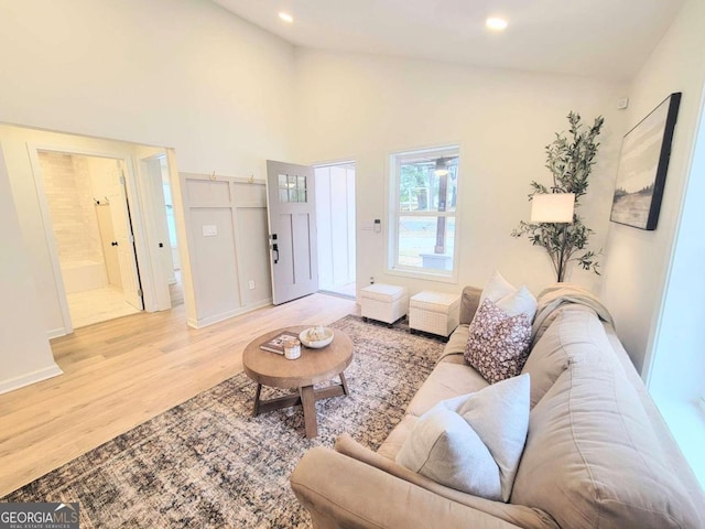 living room featuring high vaulted ceiling and light hardwood / wood-style floors