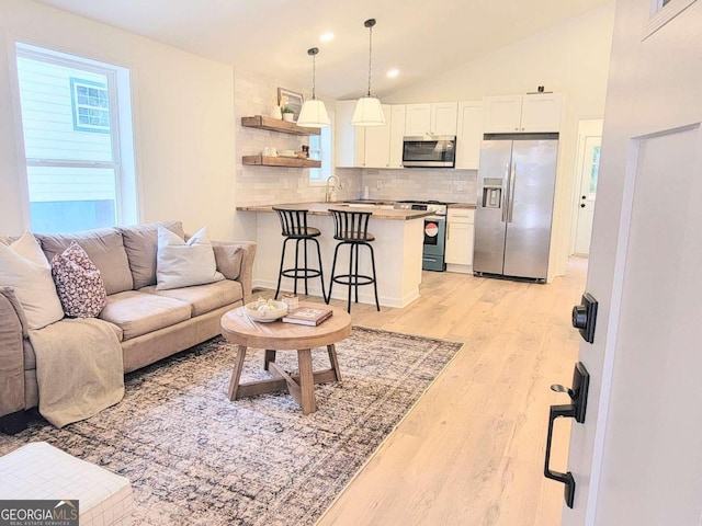 living room featuring light hardwood / wood-style floors, lofted ceiling, and sink