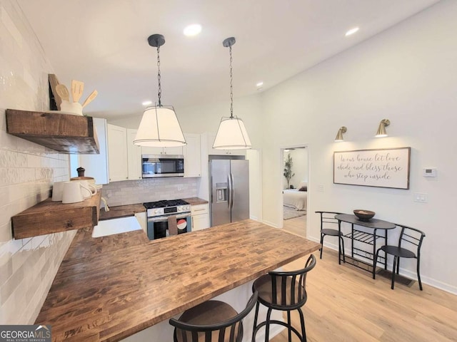 kitchen featuring light hardwood / wood-style flooring, white cabinetry, kitchen peninsula, and stainless steel appliances