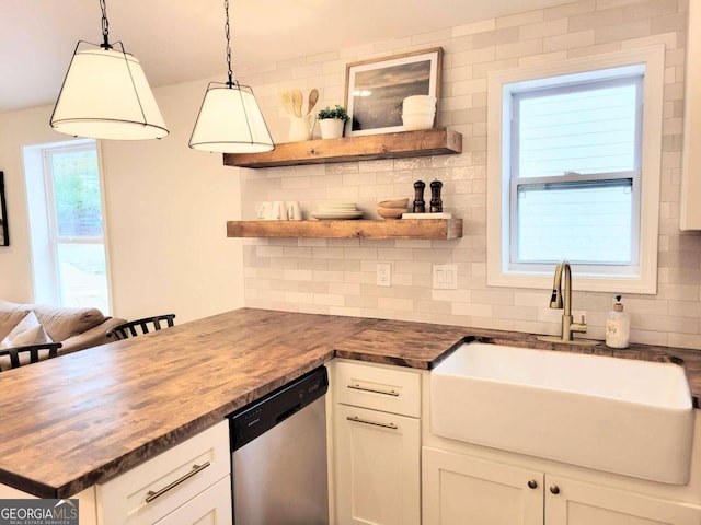 kitchen with stainless steel dishwasher, white cabinetry, butcher block countertops, and decorative light fixtures