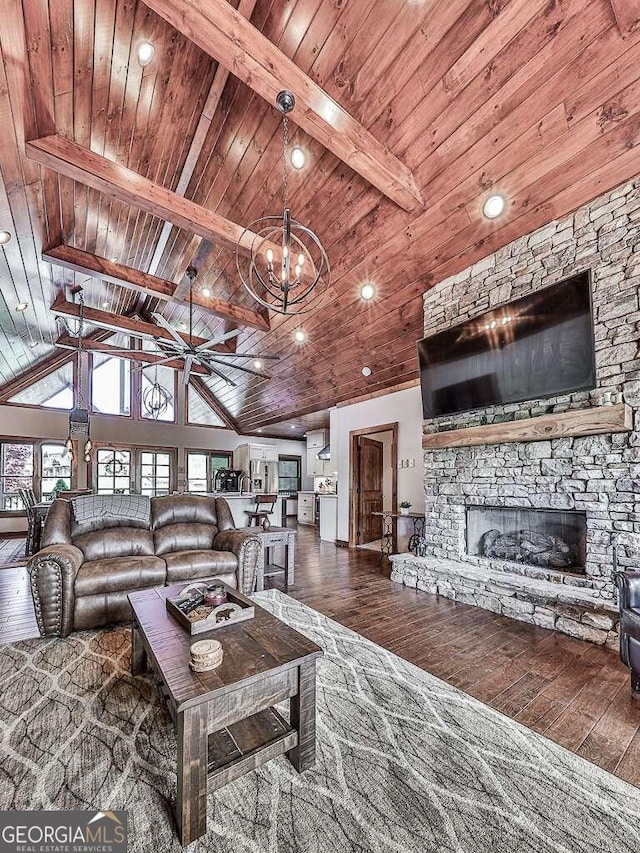 living room with beam ceiling, hardwood / wood-style floors, a stone fireplace, wood ceiling, and a chandelier