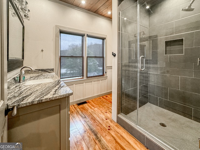 bathroom featuring vanity, wood-type flooring, a shower with door, and wood ceiling