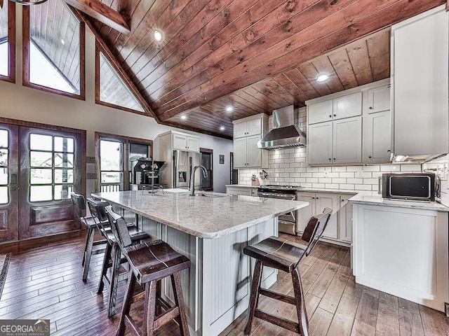 kitchen with wooden ceiling, wall chimney exhaust hood, stainless steel range oven, a kitchen island with sink, and dark wood-type flooring