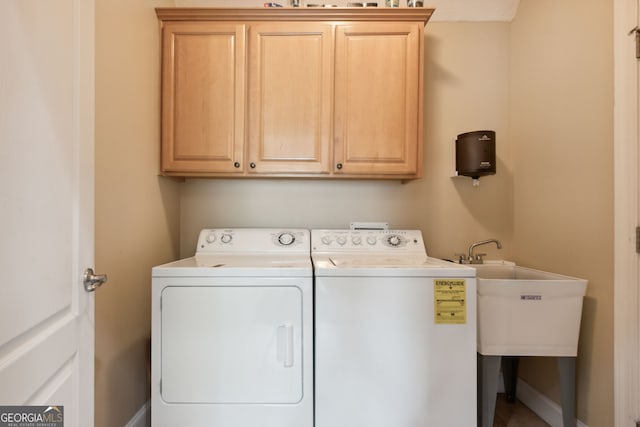 clothes washing area featuring cabinets, sink, and independent washer and dryer