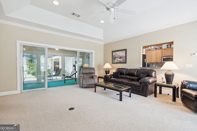 living room featuring ornamental molding, a raised ceiling, light carpet, and ceiling fan