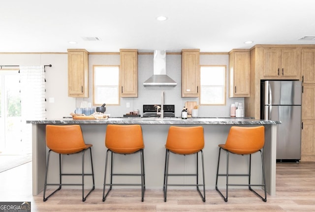646 Grande Ave, Folkston, GA 31537 - kitchen featuring wall chimney range hood, freestanding refrigerator, a breakfast bar area, an island with sink, and plenty of natural light