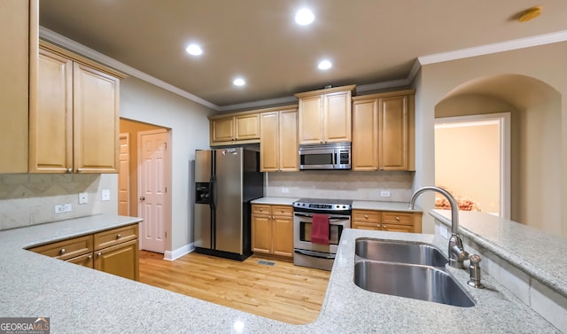 kitchen featuring sink, light wood-type flooring, stainless steel appliances, and ornamental molding