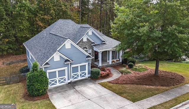 view of front of property featuring covered porch, a garage, and a front lawn