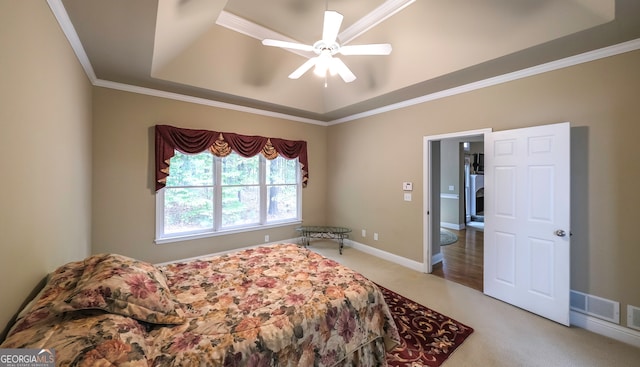 carpeted bedroom with ceiling fan, ornamental molding, and a tray ceiling