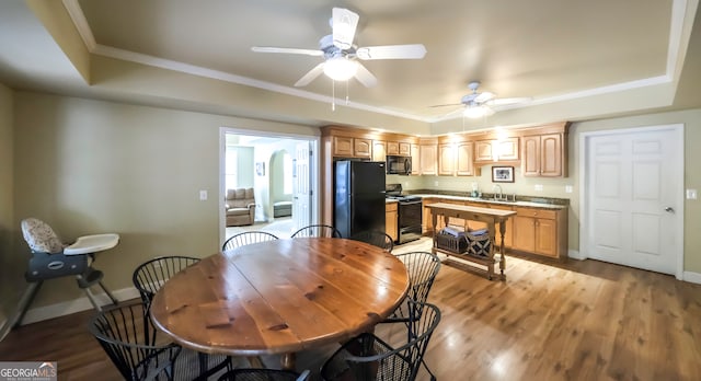 dining room featuring ceiling fan, sink, a raised ceiling, crown molding, and light wood-type flooring