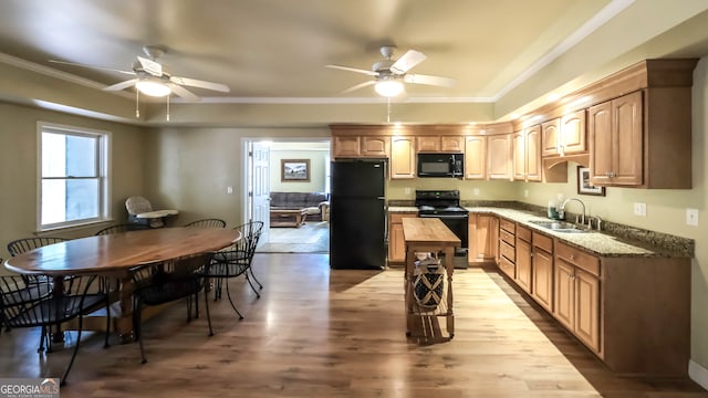 kitchen featuring light stone countertops, sink, crown molding, black appliances, and light wood-type flooring