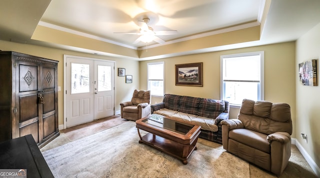 living room with ceiling fan, ornamental molding, light carpet, and a tray ceiling