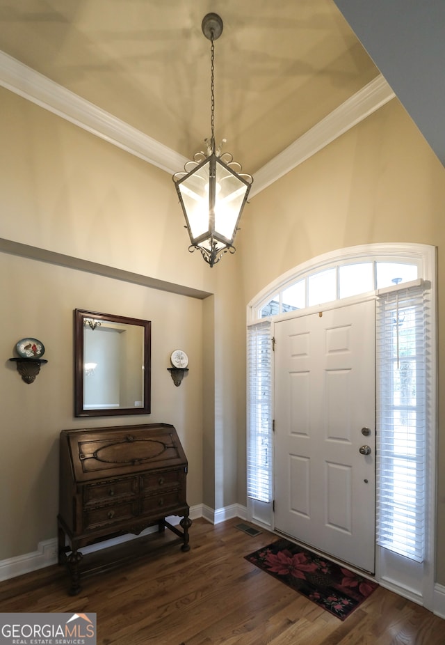 foyer entrance with crown molding, dark hardwood / wood-style flooring, and an inviting chandelier