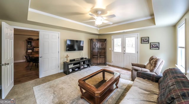 living room featuring plenty of natural light, ceiling fan, and a raised ceiling