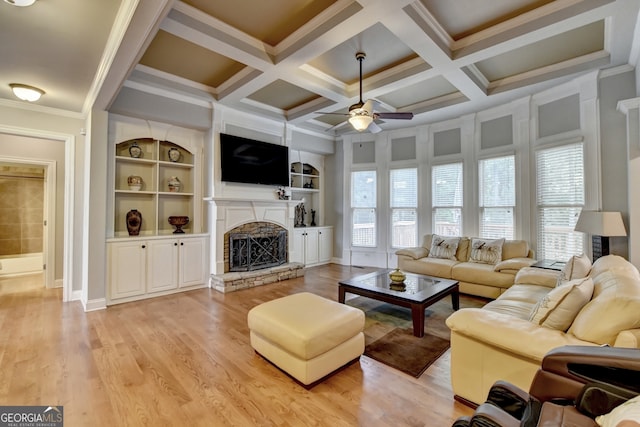 living room featuring ceiling fan, a fireplace, light hardwood / wood-style flooring, crown molding, and built in features