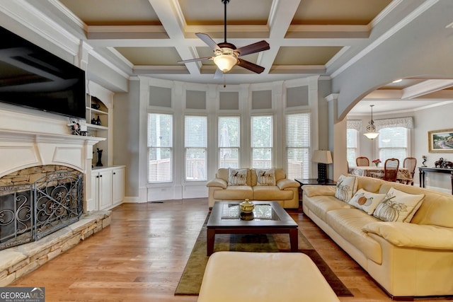 living room with a stone fireplace, light wood-type flooring, plenty of natural light, and coffered ceiling